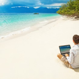 man with laptop on colorful beach of island